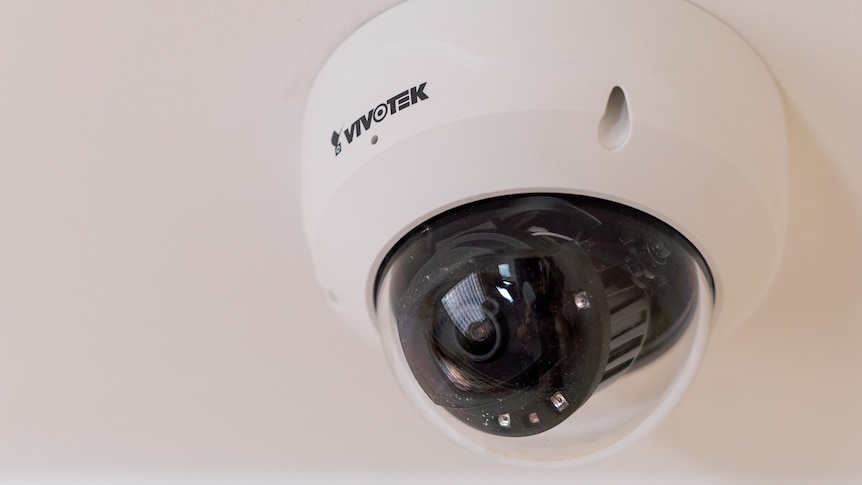A small black CCTV camera on a ceiling inside a black ball