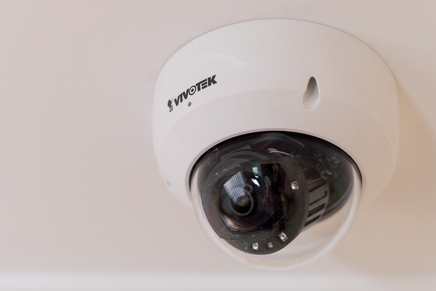 A small black CCTV camera on a ceiling inside a black ball