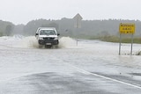 A four-wheel drive travels through a flooded highway in NSW