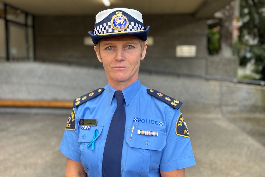A Tasmania Police woman wearing a blue uniform standing in front of a police station