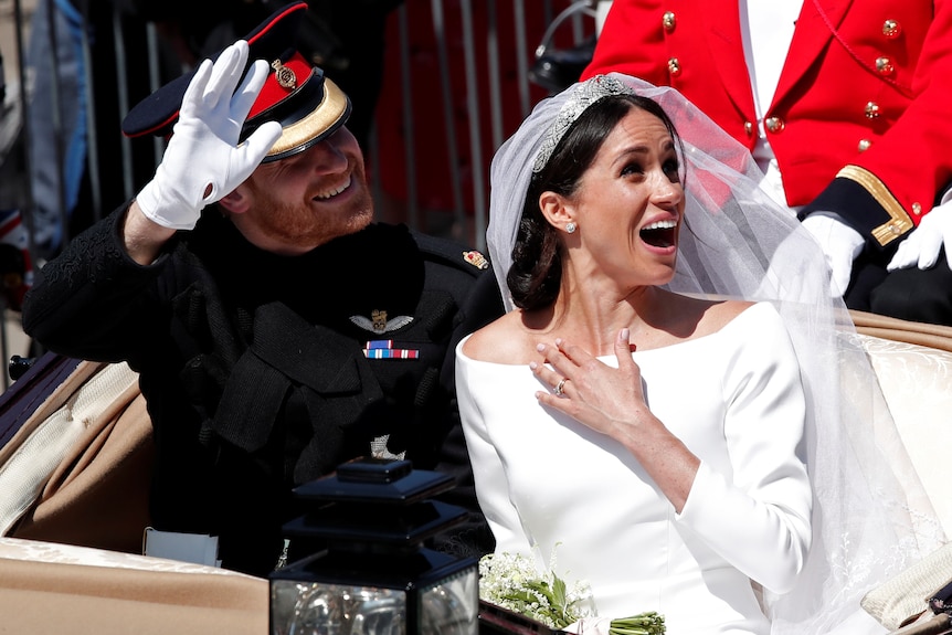 Britain's Prince Harry and his wife Meghan ride a horse-drawn carriage.