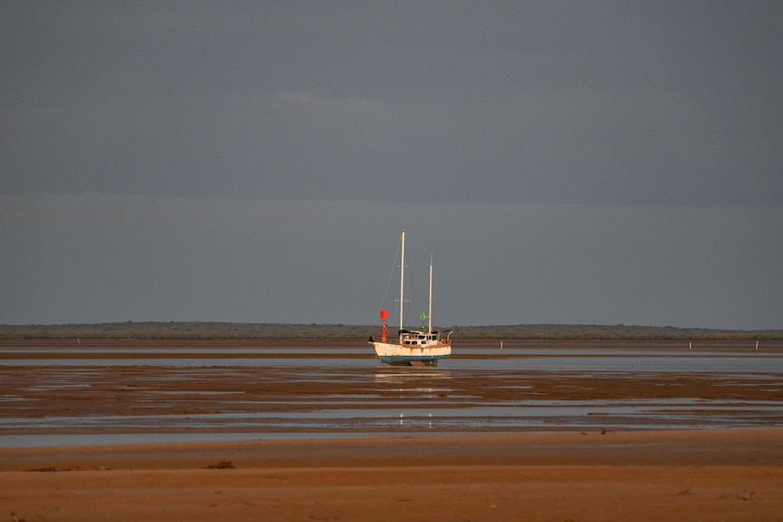 A boat sits on sand stuck at the entryway to Carnarvon's main waterway