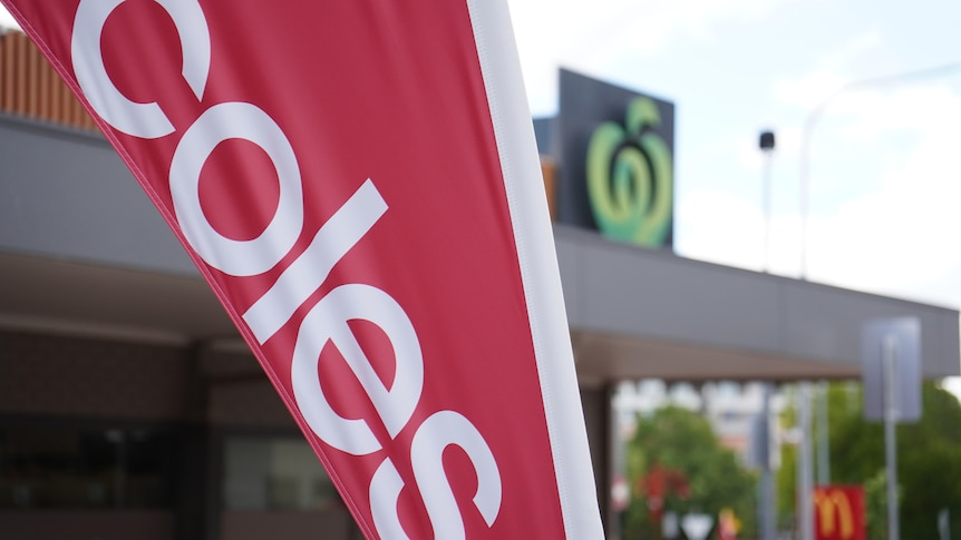 A banner reading 'Coles' and, in the background, the Woolworths logo.