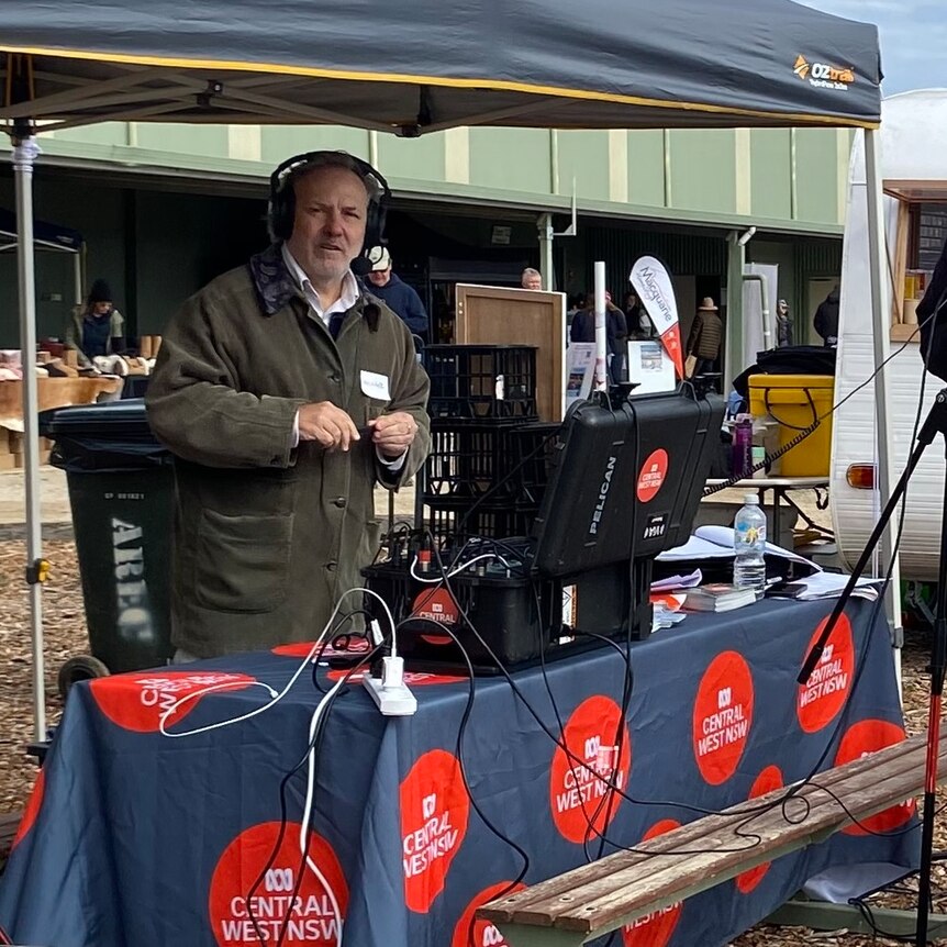 Michael standing under a canopy with broadcast equipment on a table