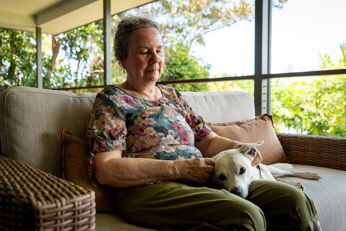 A woman sitting on a couch with a dog