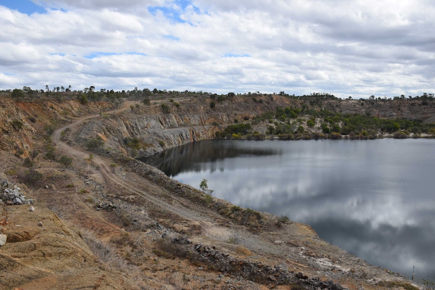 A dirt road sits follows the water filled pit