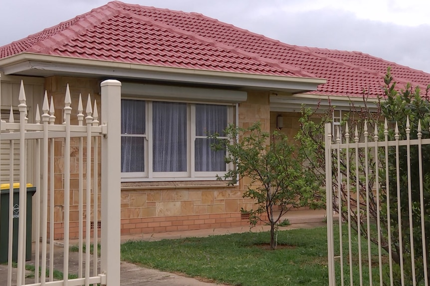 A yellow brick house with a white fence