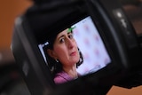 A close shot of Gladys Berejiklian is seen through the view finder on a television camera. 