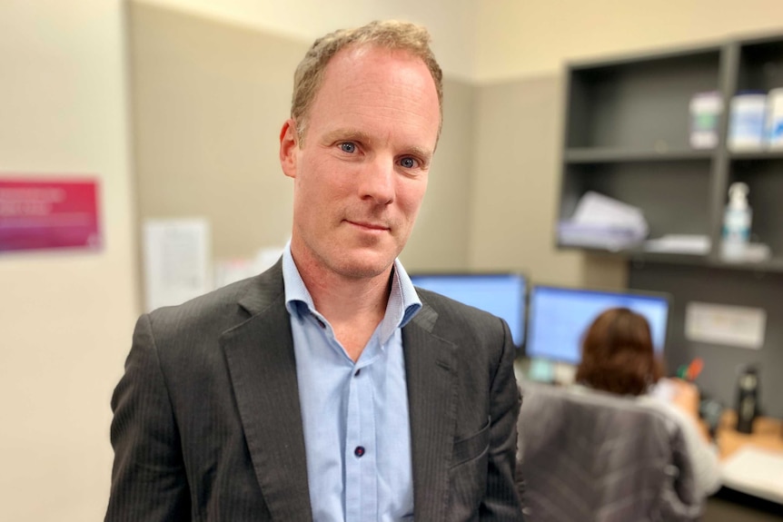 A man in a jacket looks at the camera.