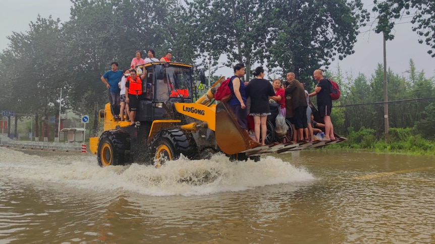 Local residents being evacuated on a forklift during China's flooding. 