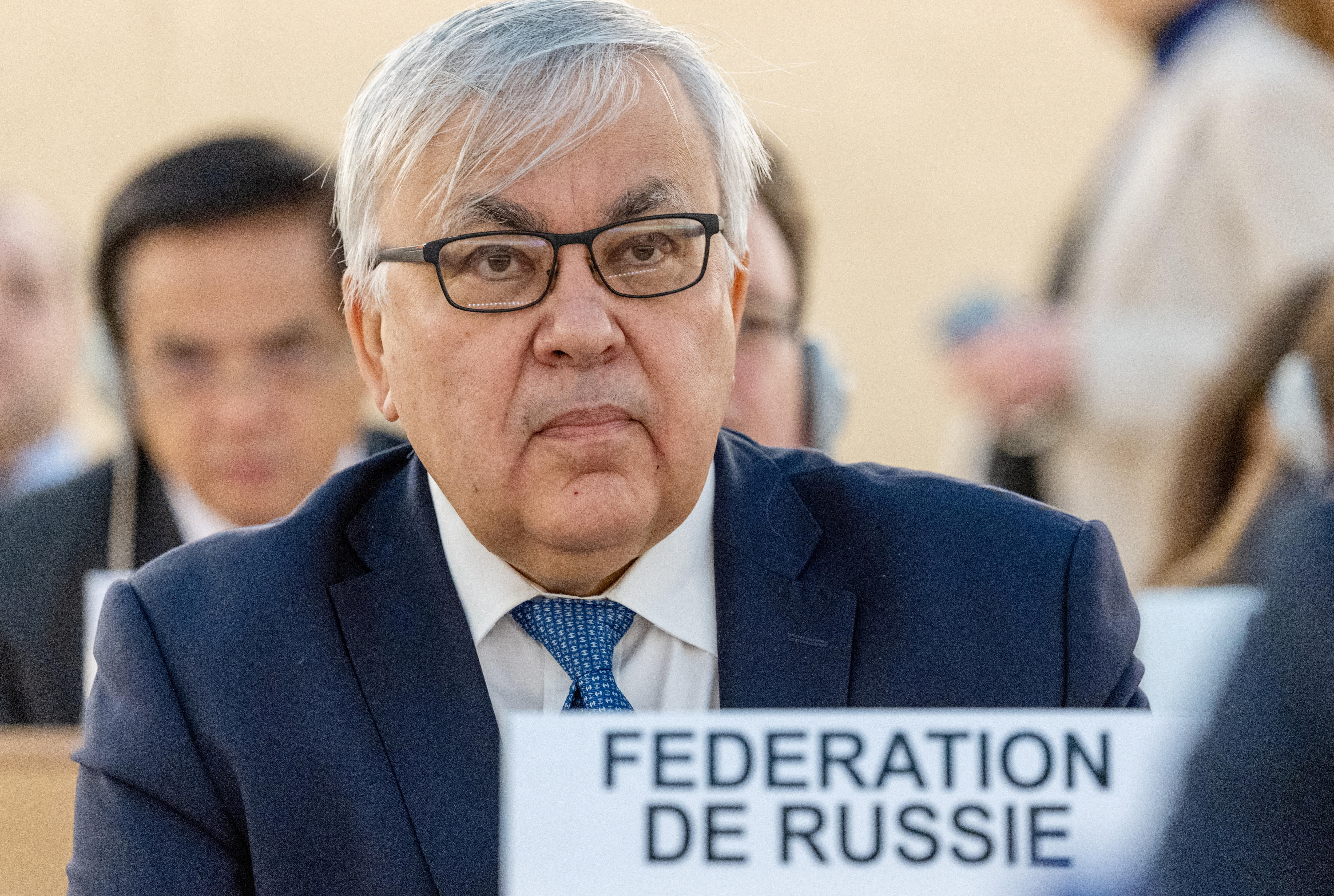 An older man with glasses sits at the seat earmarked for Russia at the UN Human Rights Council.