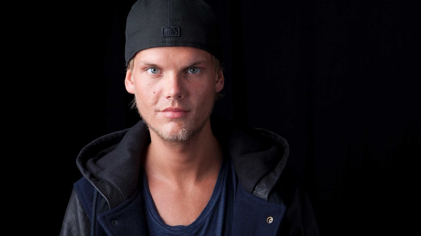 Avicci stands in front of a black background.
