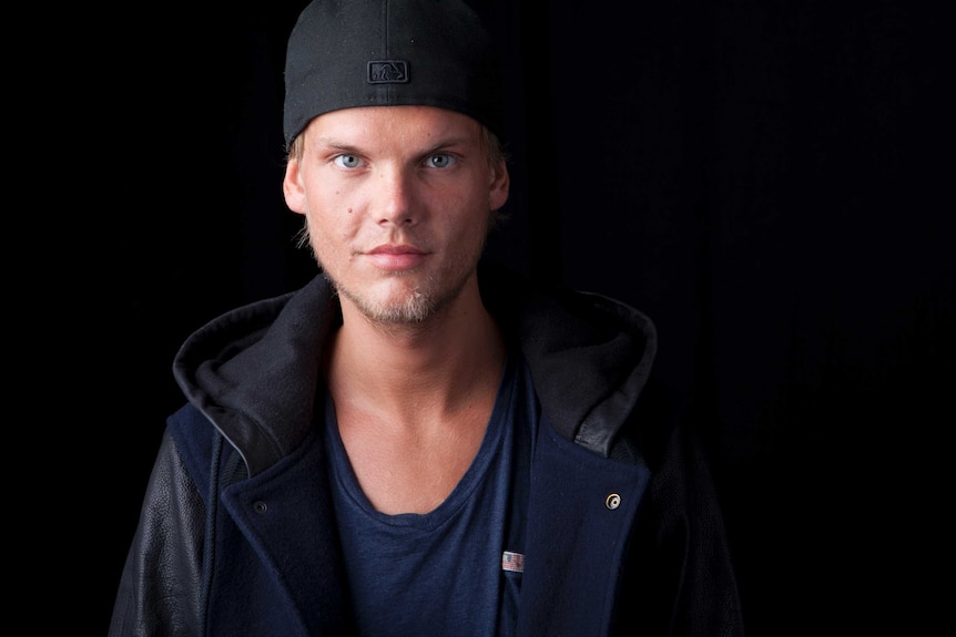 Avicci stands in front of a black background.