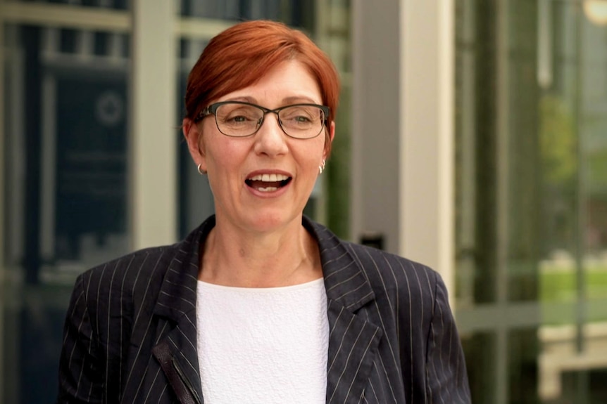 A woman with red hair and glasses.