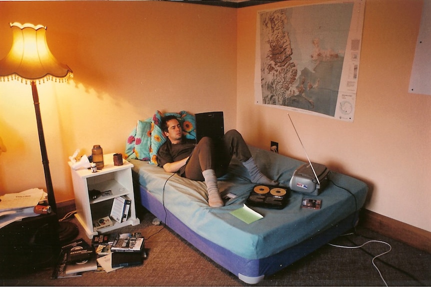 Nicholas Johnson writing on his bed.