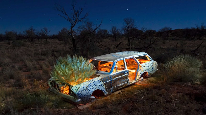 An abandoned car in the bush painted and lit internally with candles