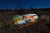 An abandoned car in the bush painted and lit internally with candles