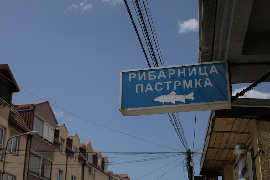 A sign for a business with Cyrillic writing and an outline of a fish