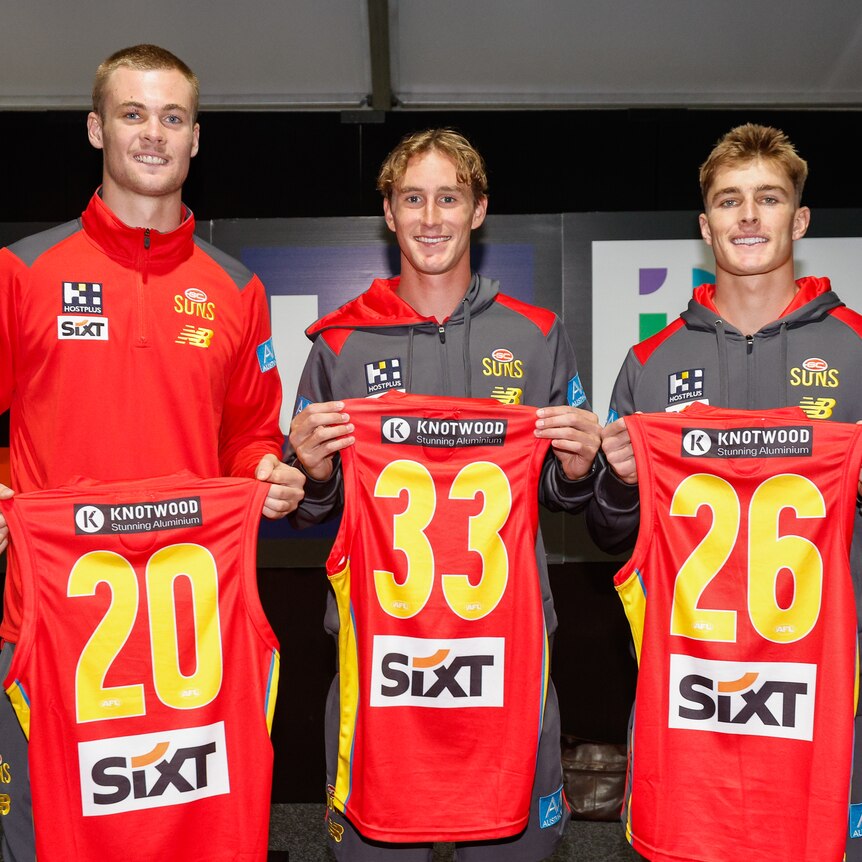 Ethan Read, Sam Clohesy and Will Graham hold their new Gold Coast jerseys