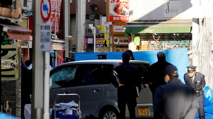 Policemen stand next to a car sat amid Tokyo shops