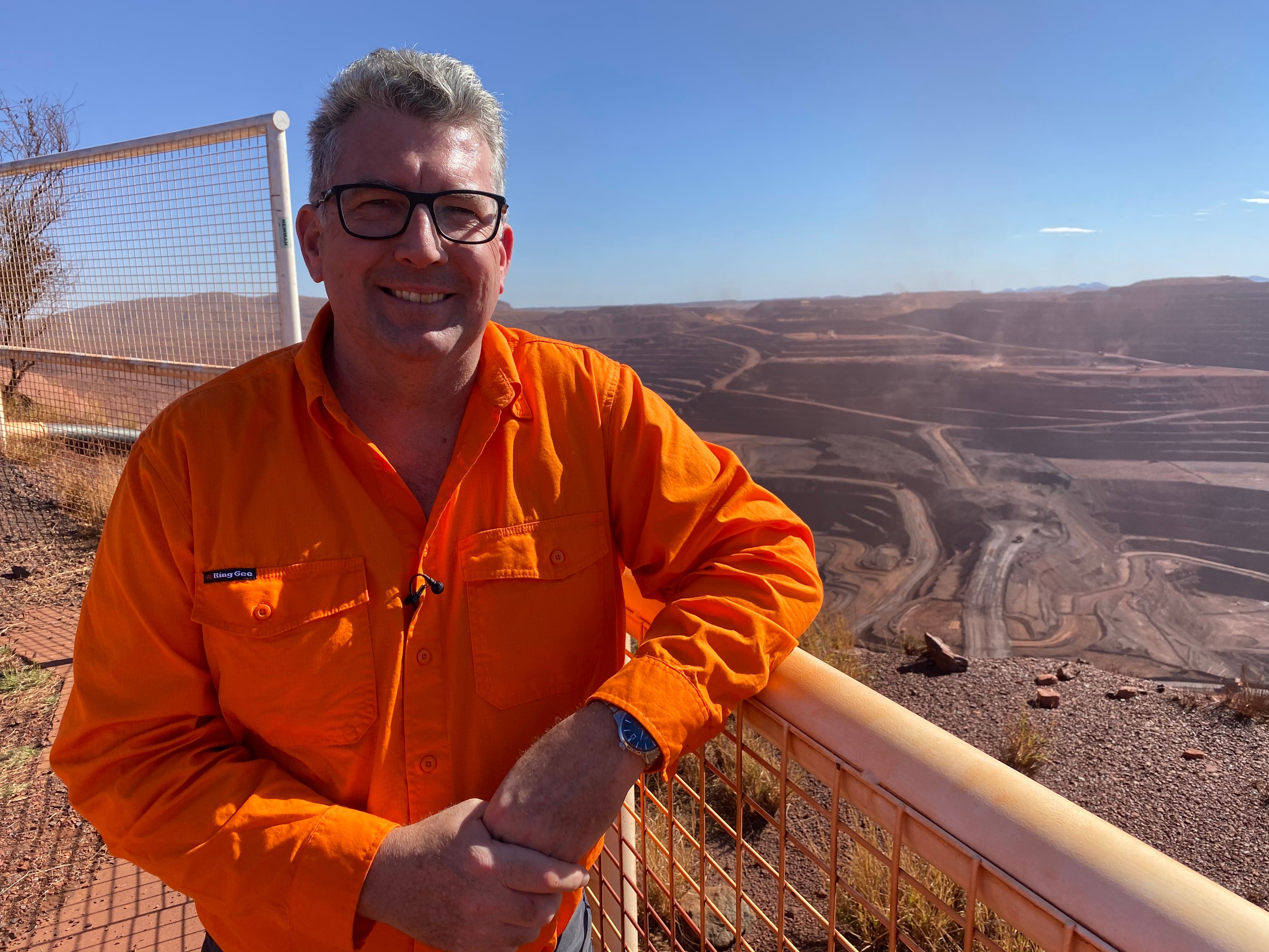Federal Resources Minister Keith Pitt stands at a lookout with BHP's Mt Whaleback mine behind and below him.