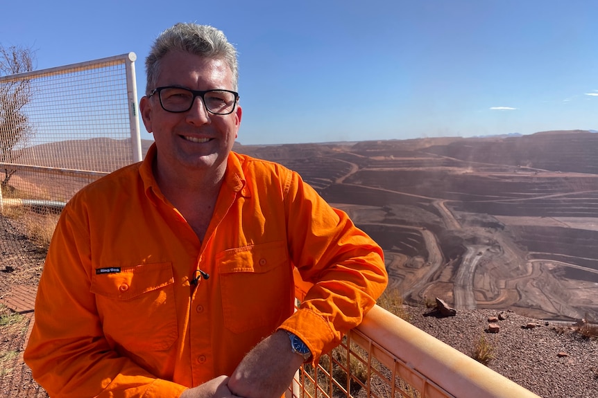 Federal Resources Minister Keith Pitt stands at a lookout with BHP's Mt Whaleback mine behind and below him.