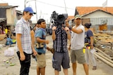 Corey Pearson stands in an Indonesian street with three assistants, one holding a camera, on set.