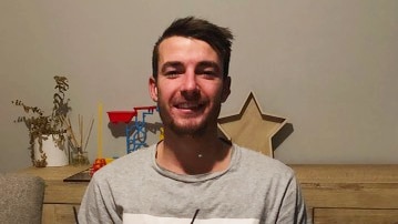 Cameron Smith smiles as he sits in front of a birthday cake.