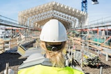 A woman in a hard hat looks at a construction site