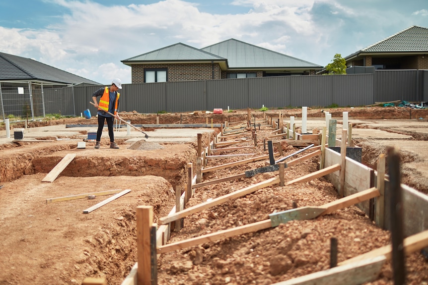 A man raking dirt at a construction site.