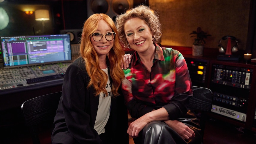 Tori Amos and Zan Rowe sit side by side in a recording studio smiling at the camera