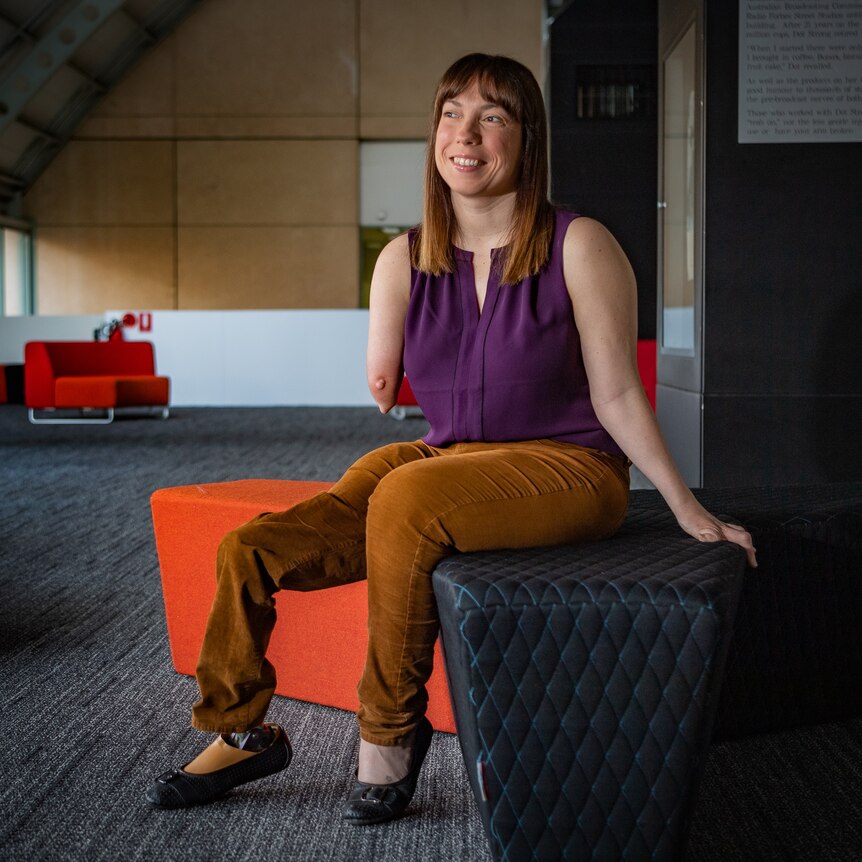 A woman with a prosthetic leg and limb difference sitting down
