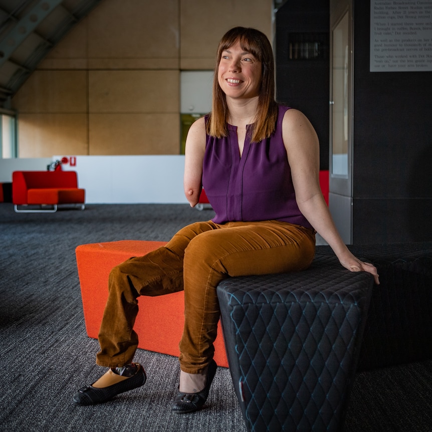 A woman with a prosthetic leg and limb difference sitting down