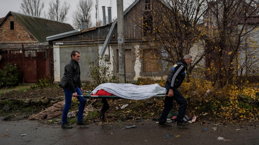 City workers collect the body of a man in Kherson.