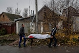 City workers collect the body of a man in Kherson.