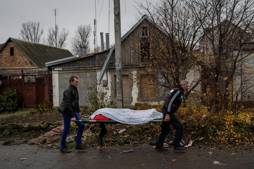 I lavoratori della città raccolgono il cadavere di un uomo a Kherson.