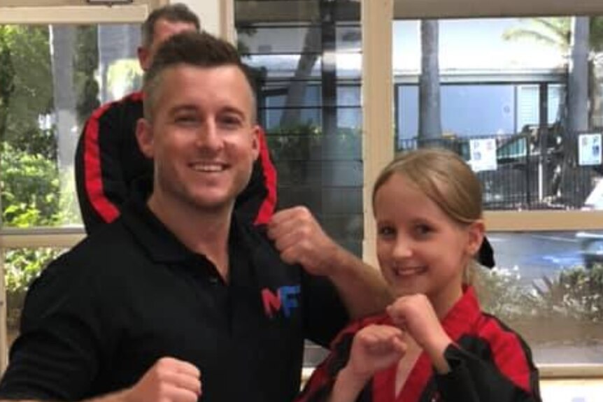 Man and a young girl pose with fists up