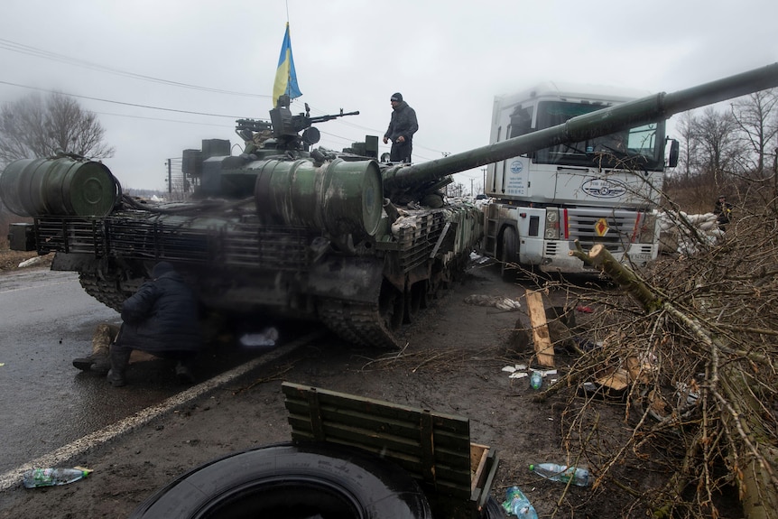 A Ukrainian serviceman stands on top of a captured Russian tank in the north of the Kharkiv regio