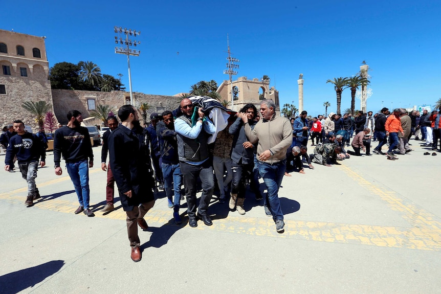 On a bright blue day, a large group of people carry