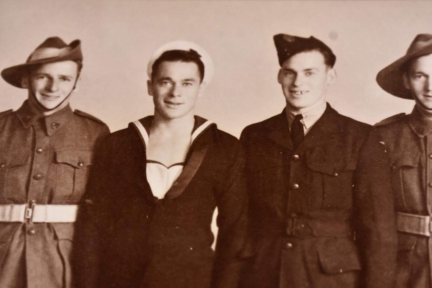 Sepia photo of four men in army, navy and air force uniforms from the second world war.