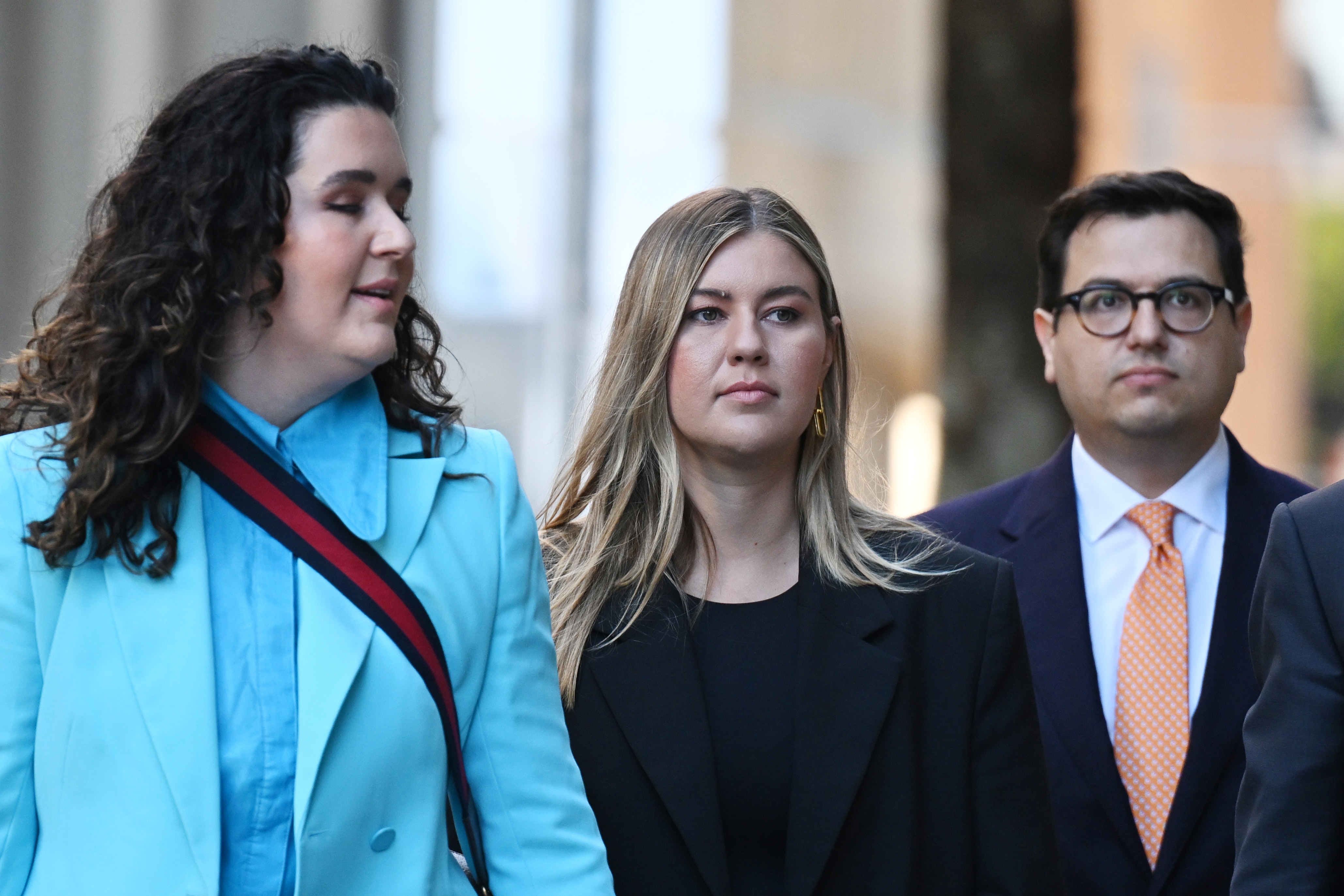 Brittany Higgins walking with a friend and her fiance on either side of her.