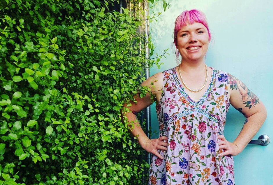 Clementine Ford stands next to a hedge.