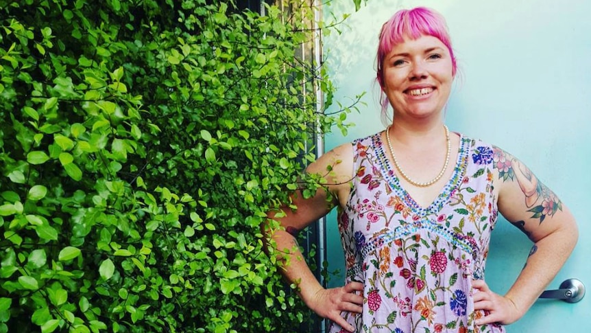 Clementine Ford stands next to a hedge.