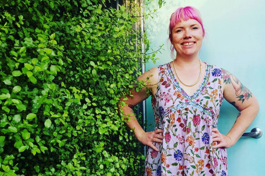 Clementine Ford stands next to a hedge.