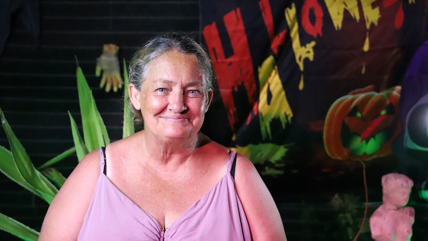 A woman, looking at the camera and smiling with a Halloween poster in the background