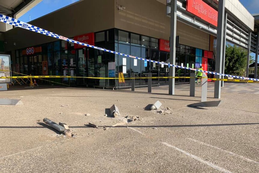 Smashed bollards and police tape at scene where a person used a front-end loader to steal an ATM.