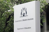 Large white sign outside the Department of Education offices in East Perth, surrounded by trees.