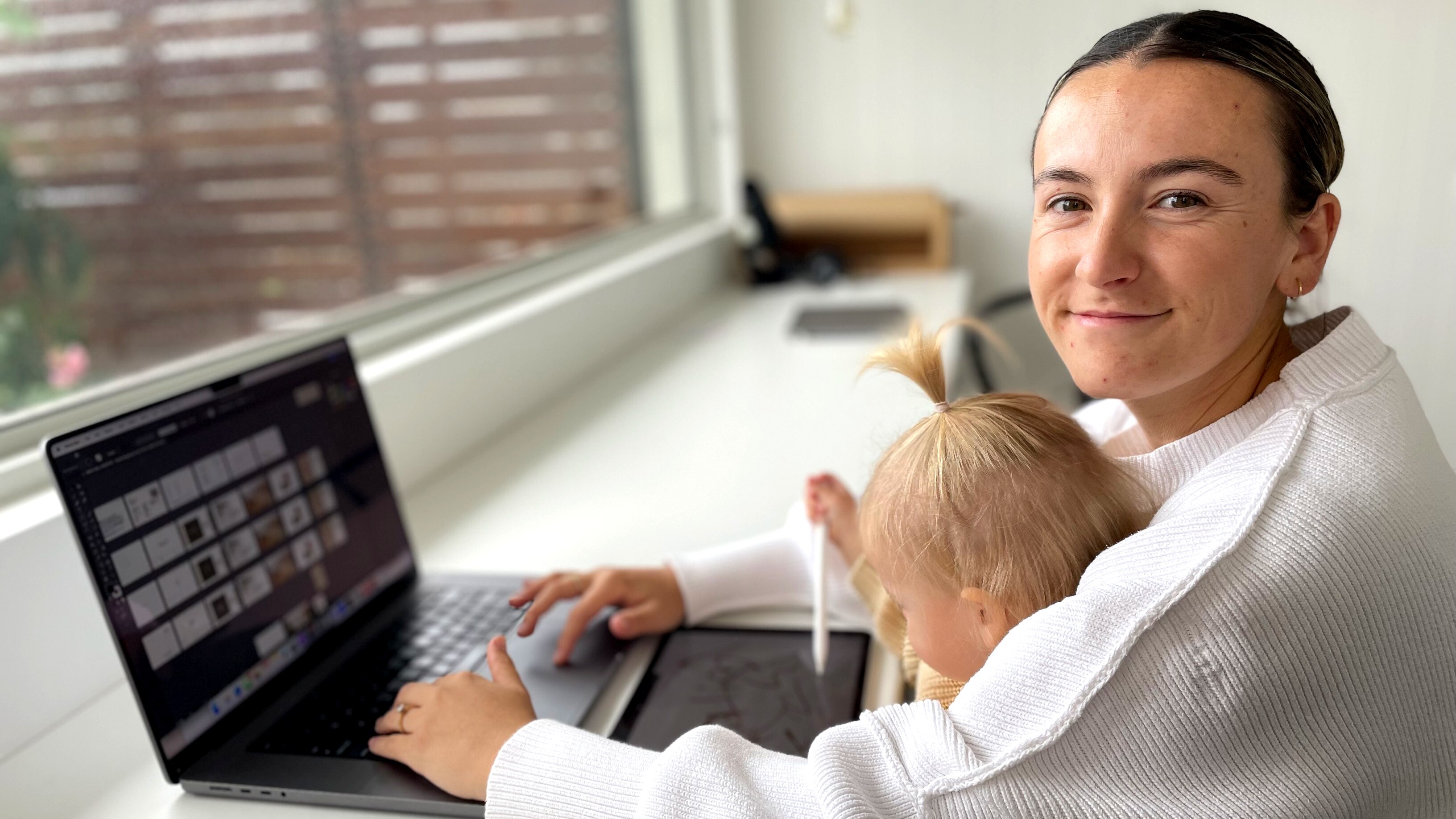 Ebony Forsyth works on her laptop. Her baby is on her lap.