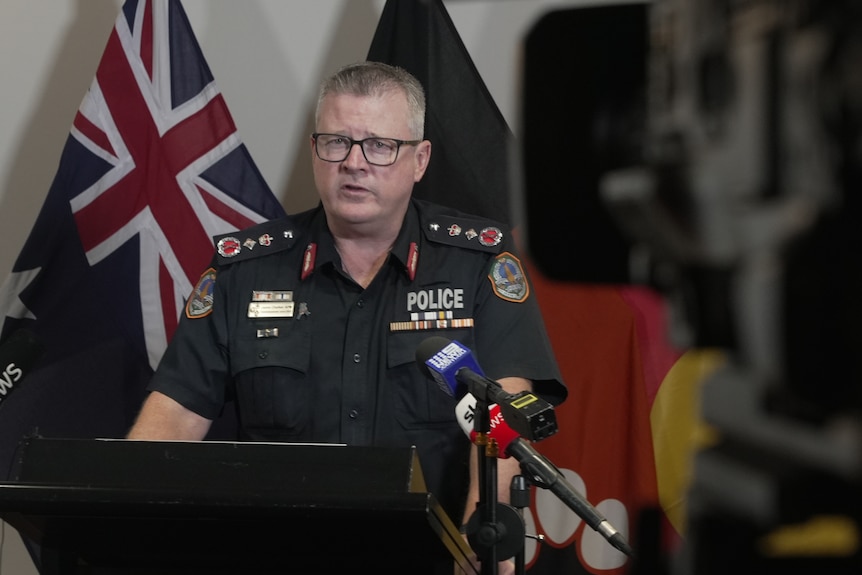 A middle-aged Caucasian man in a police uniform wearing glasses