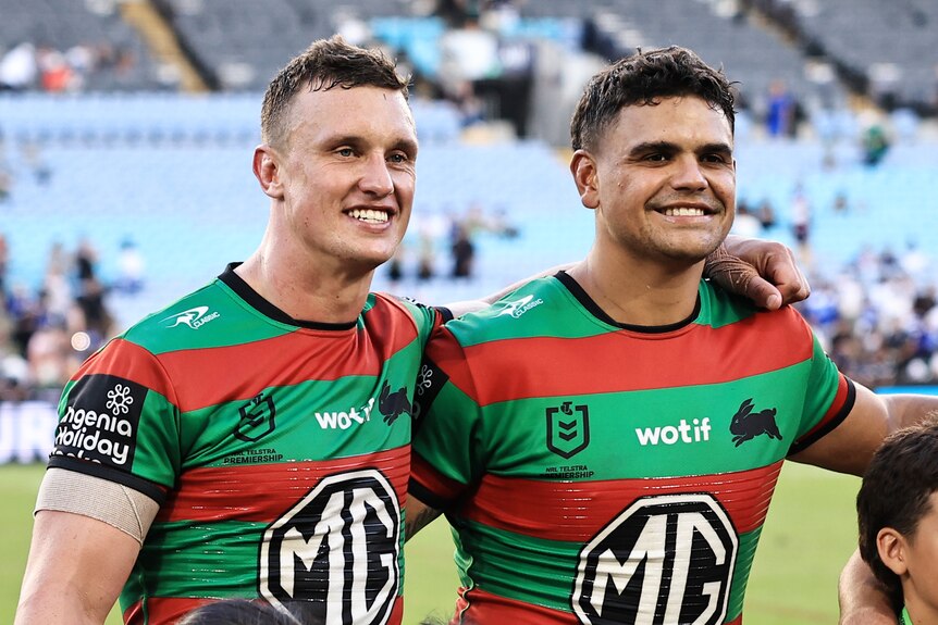 Jack Wighton and Latrell Mitchell stand arm in arm at a South Sydney Rabbitohs NRL game.